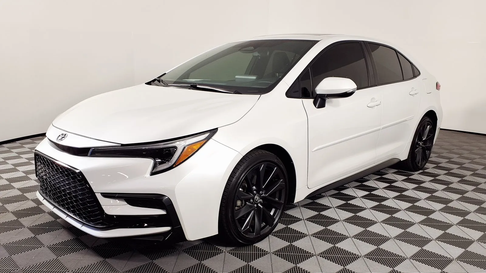 White Toyota Corolla Hybrid SE sedan, front three-quarter view, in a dealer showroom