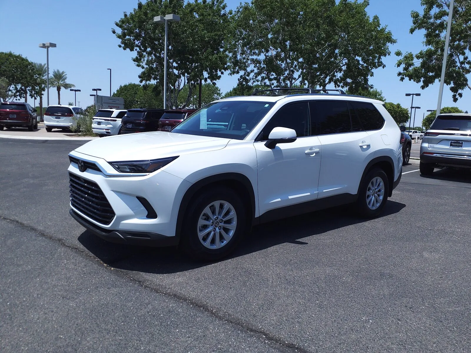 White 2024 Toyota Grand Highlander XLE, front three-quarter view on a dealer lot