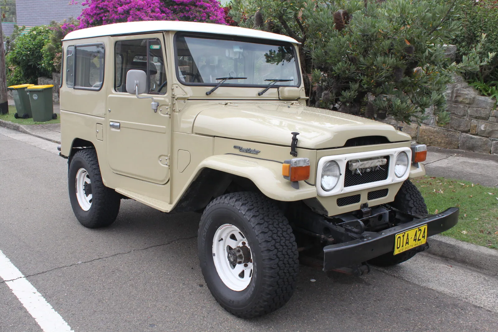 Beige 1980 Toyota Land Cruiser FJ40 hardtop parked at a kerb, front three-quarter view