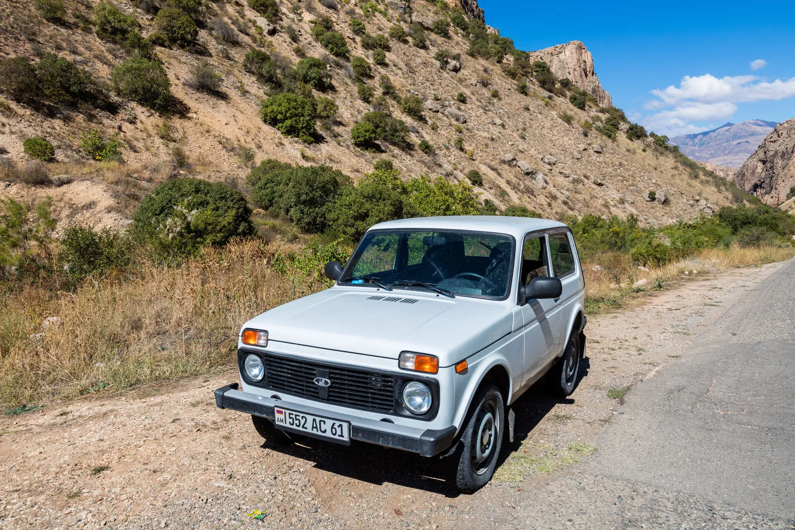 Silver Lada Niva parked on a mountain road near the Noravank monastery in Armenia