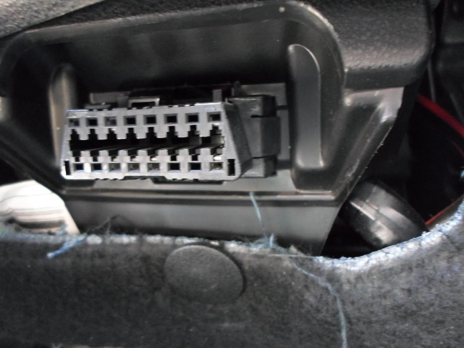 De 16-polige OBD2-diagnoseaansluiting onder het dashboard van een auto