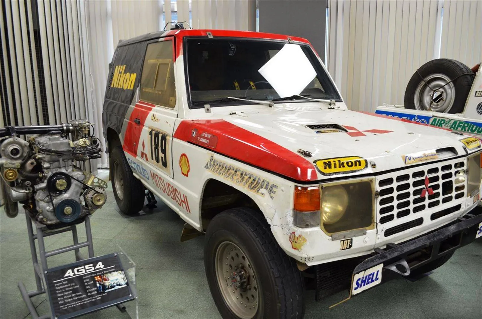 First-generation Mitsubishi Pajero rally car in white and red livery, the 1985 Paris–Dakar winner, on display in a museum