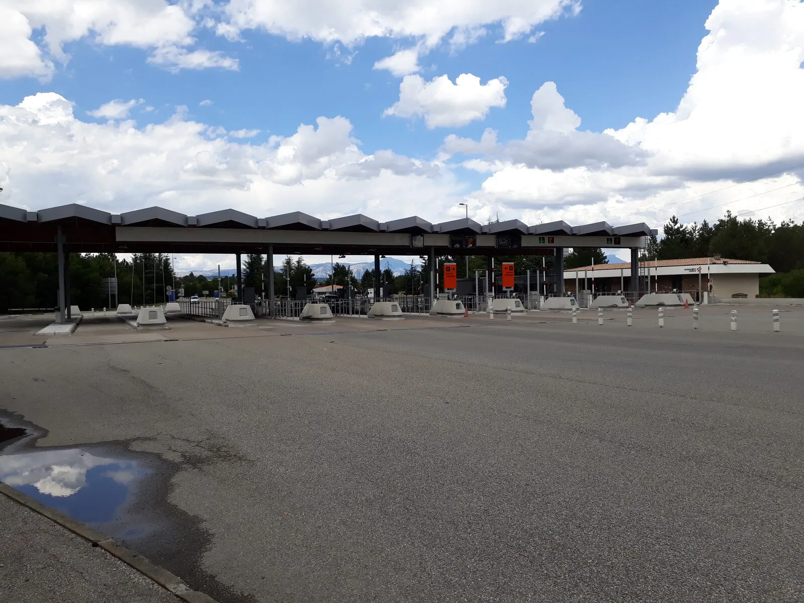 An empty motorway toll plaza under a cloudy sky
