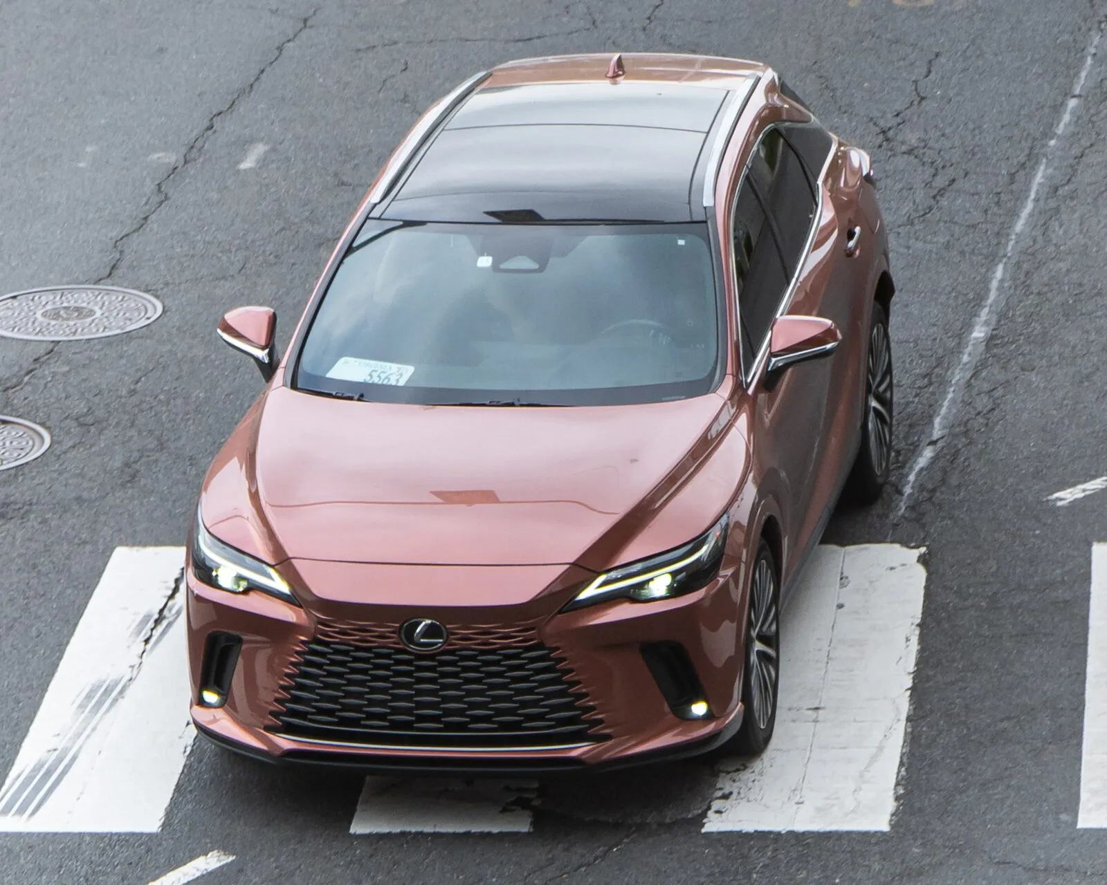 Copper-colored Lexus RX 350h, fifth generation, front view crossing a street in the Washington, DC area
